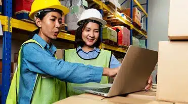 Jeune alternante en supply chain et logistique avec son maitre d'apprentissage dans un hangar de livraison